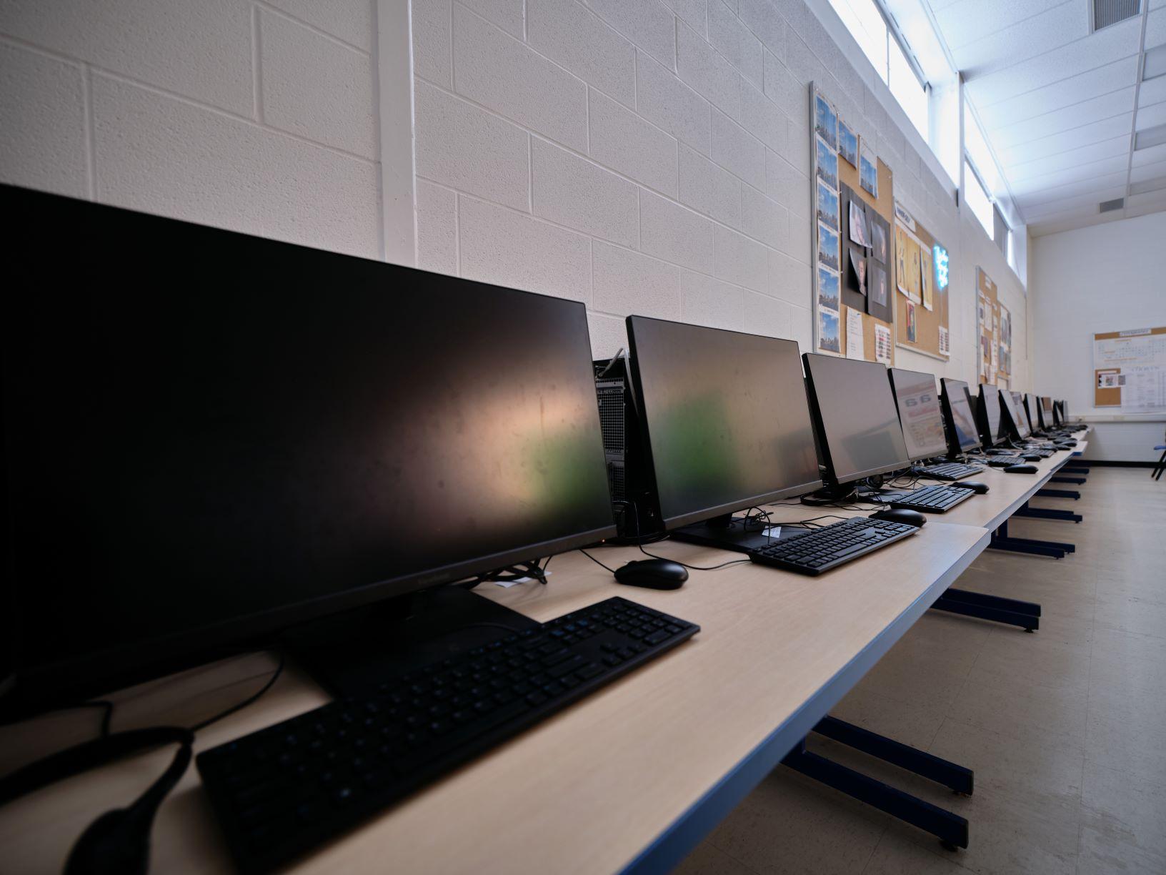 row of computer screens sit on a table