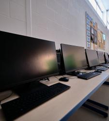 row of computer screens sit on a table