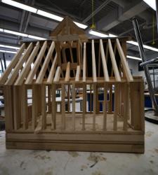 small frame of wooden house sits on table